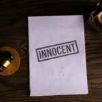 Close-up of legal document stamped 'Innocent' beside a gavel on a wooden desk.